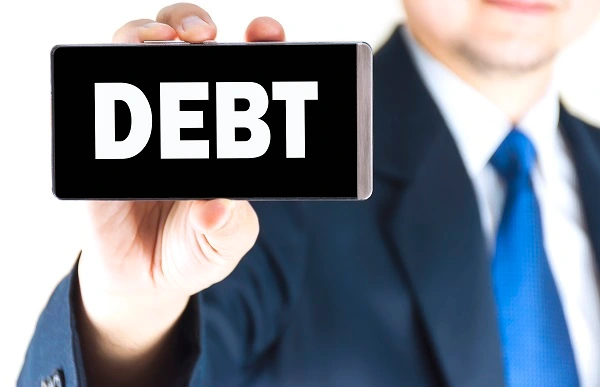 Businessman holding a smartphone displaying the word "DEBT", representing cross-border financial claims and the process to enforce debt collection in Turkey for foreign nationals.