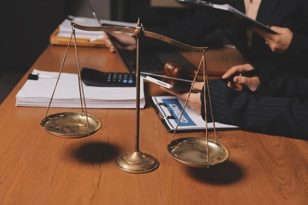 Legal professionals reviewing case files and contracts at a desk with a justice scale in focus, symbolizing the legal process to enforce debt collection in Turkey for foreigners.