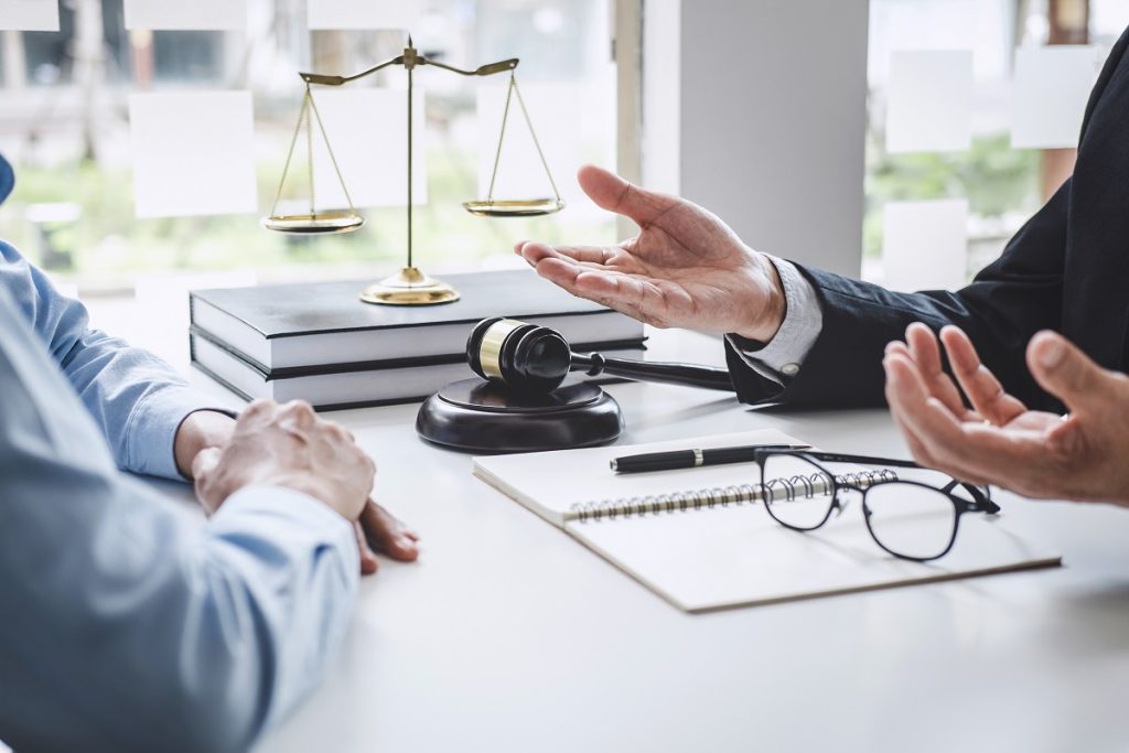 A lawyer explaining legal procedures to a client at a desk with legal documents, a gavel, and the scales of Justice statue—illustrating legal consultation for foreigners in Turkey regarding defective product claims and consumer rights in 2025.