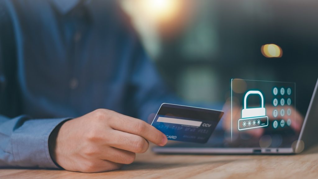 A person holding a credit card in front of a laptop with a digital security lock icon, representing safe online shopping and legal protection for foreigners in Turkey who purchase defective products.