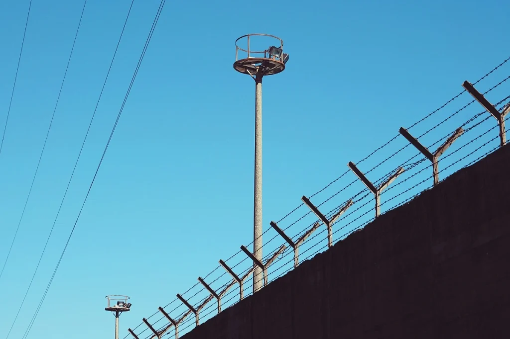 A watchtower and barbed wire fence at a Antalya removal center under clear blue sky – visual representation of immigration detention facilities in Antalya