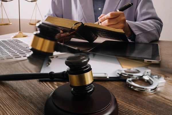 Terazi tokmak ve kitap imzalayan avukat, hukuk ve adaletle ilgili profesyonel bir görsel.