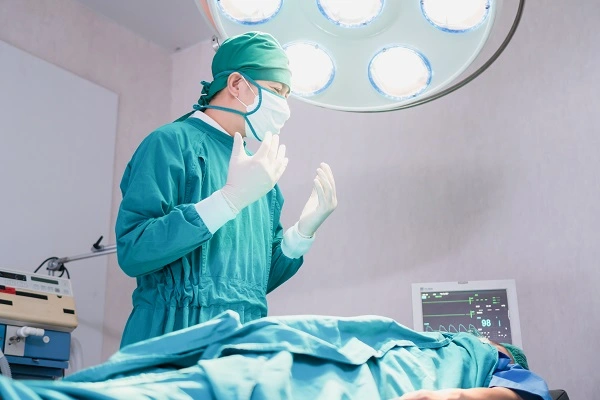 Photo of a surgeon in the operating room during a liposuction malpractice case in Turkey, standing with raised hands under surgical lights.